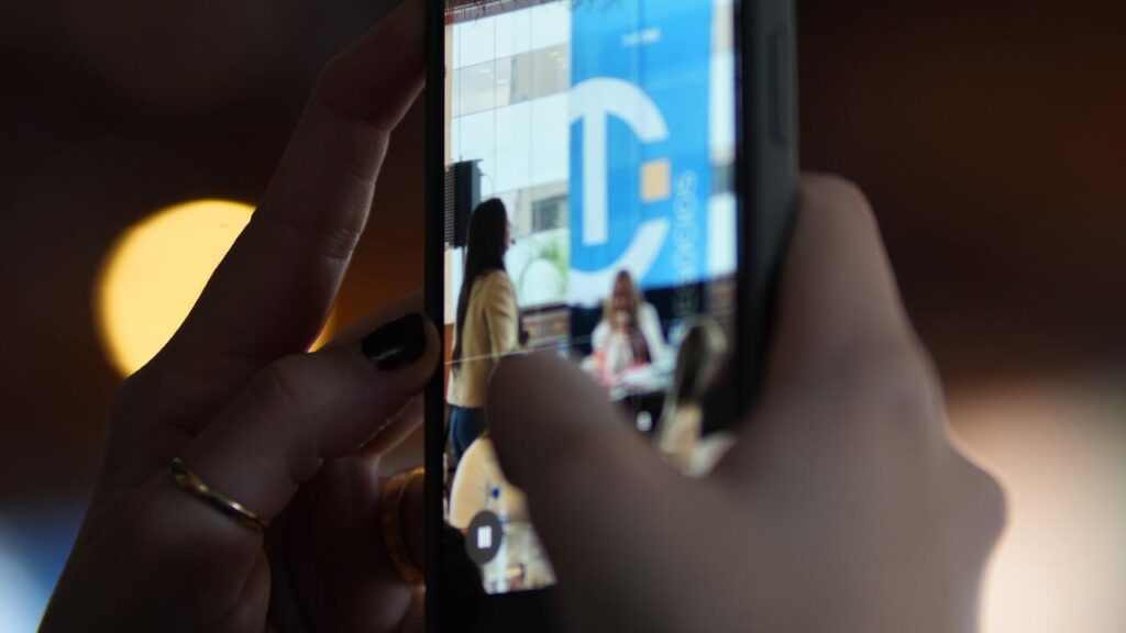 Celular smartphone gravando apresentação de Deborah Perrella sobre comunicação empresarial durante imersão Encantamento Disney+